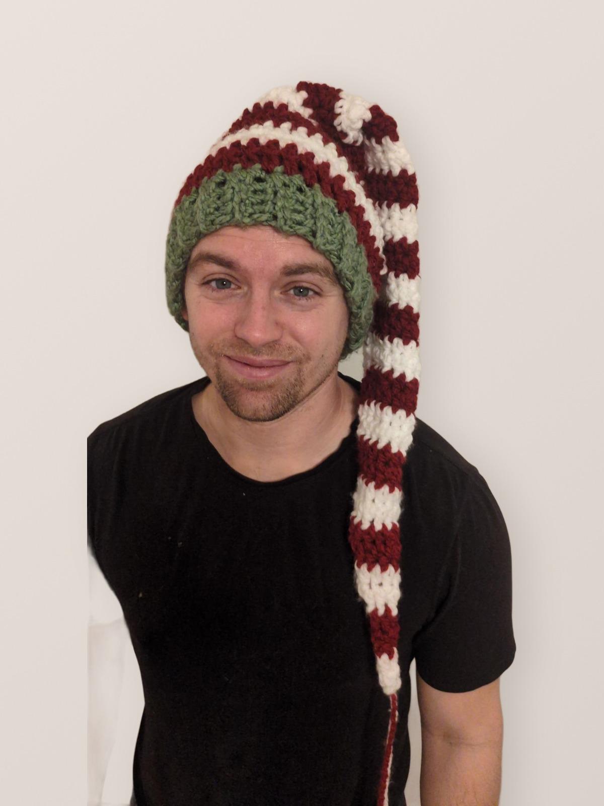 Adult wearing a long red, white, and green crochet elf hat