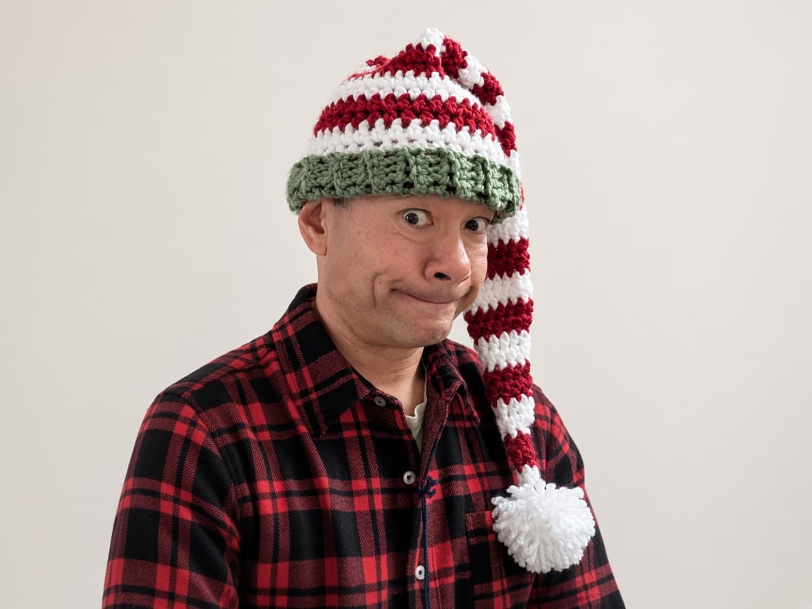 Handmade red and white striped crochet elf hat with green brim